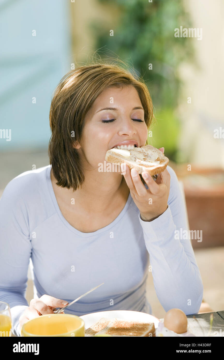 Woman, sit young, brunette, breakfast table, butter toast eat, eyes closed, model released, Stock Photo