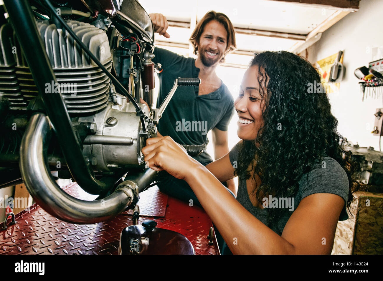 Man watching woman repairing motorcycle in garage Stock Photo