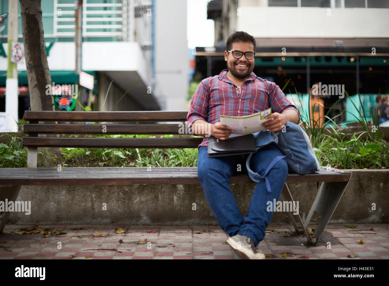 Hispanic man sitting on bench reading brochure Stock Photo