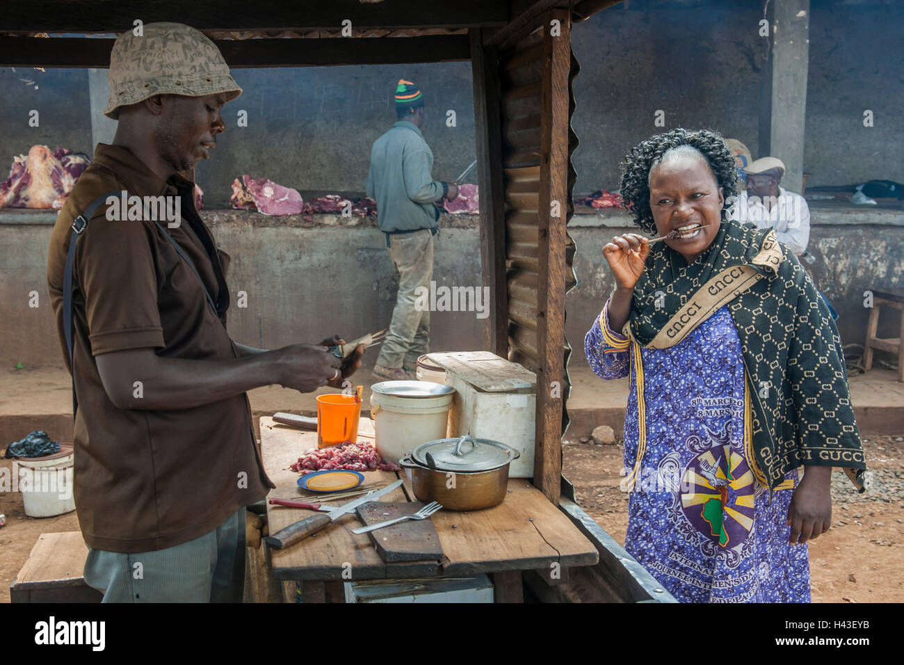 Woman eating grilled meat at street stand, street scene, Bamenda, North-West Region, Cameroon Stock Photo