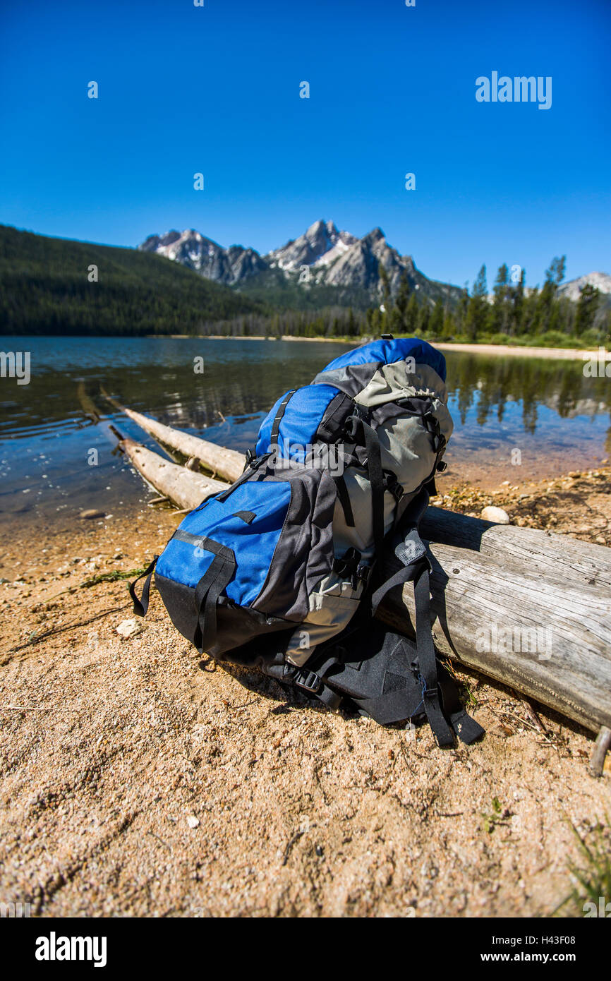 Backpack leaning on log near river Stock Photo