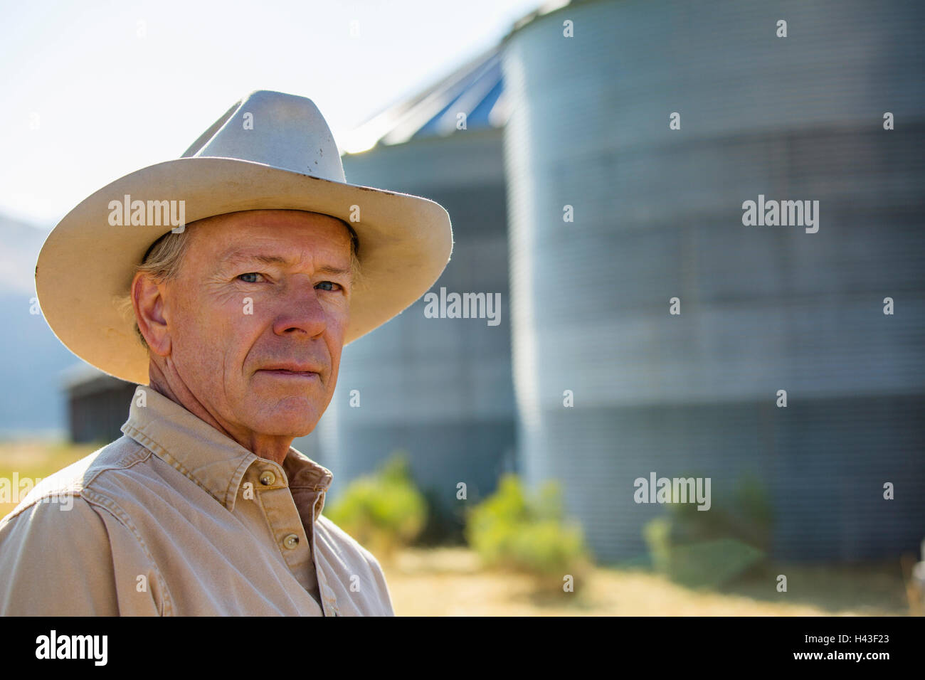Serious Caucasian farmer near storage silos Stock Photo