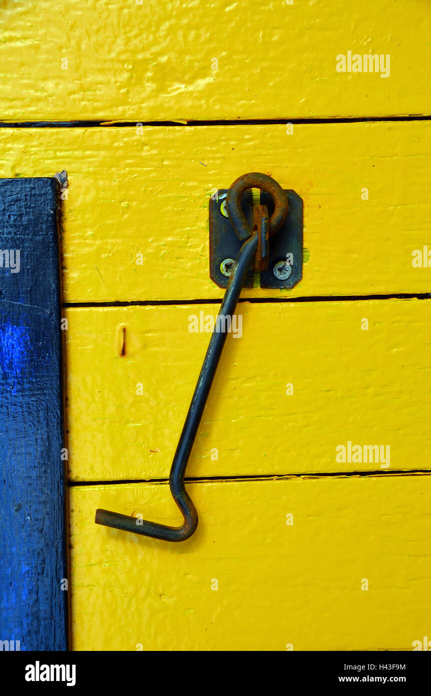 close up of a black cabin hook against  bright yellow painted wooden panels. Stock Photo