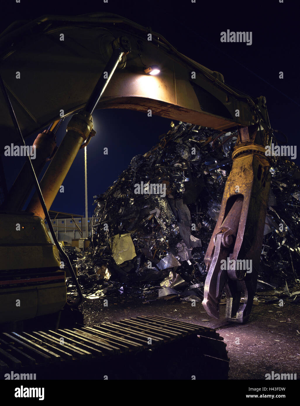 Mechanical grabber in junkyard at night Stock Photo