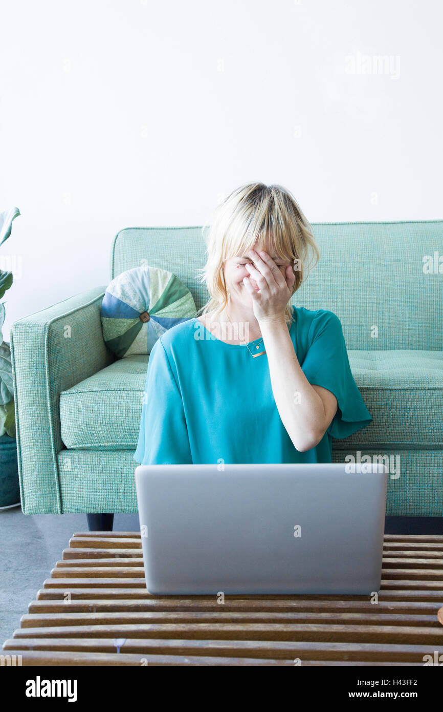 Laughing Caucasian woman sitting on floor using laptop Stock Photo