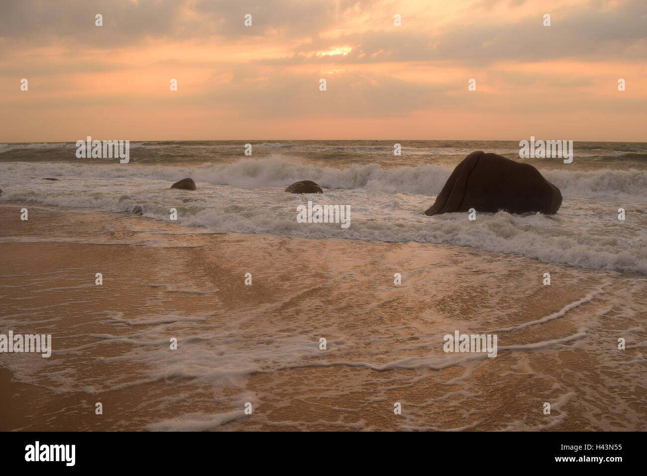 tropical beach in sunset with wave and rock Stock Photo - Alamy