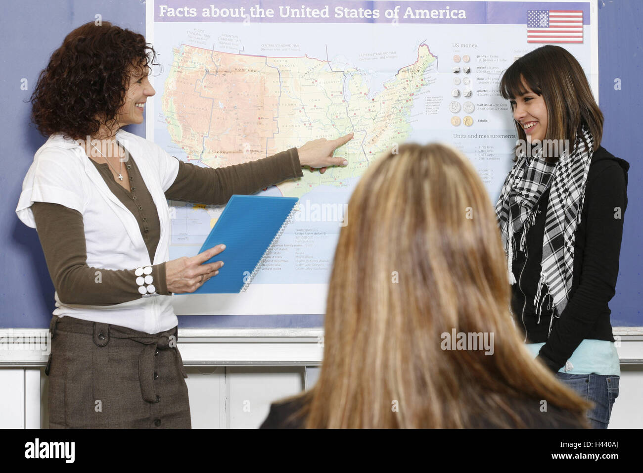 Classrooms, lessons, teacher, map, schoolgirl, point, smile, model released, school, school lessons, teenager, girl, woman, person, eye contact, stand, declare, happy, friendly, card, the USA, geography, education, school education, general education, learning atmosphere, Stock Photo