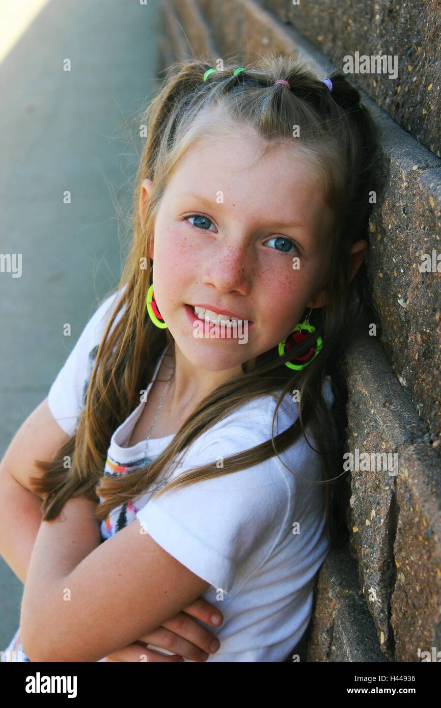 contemporary or modern portrait of a young pretty girl leaning on brick wall smiling Stock Photo