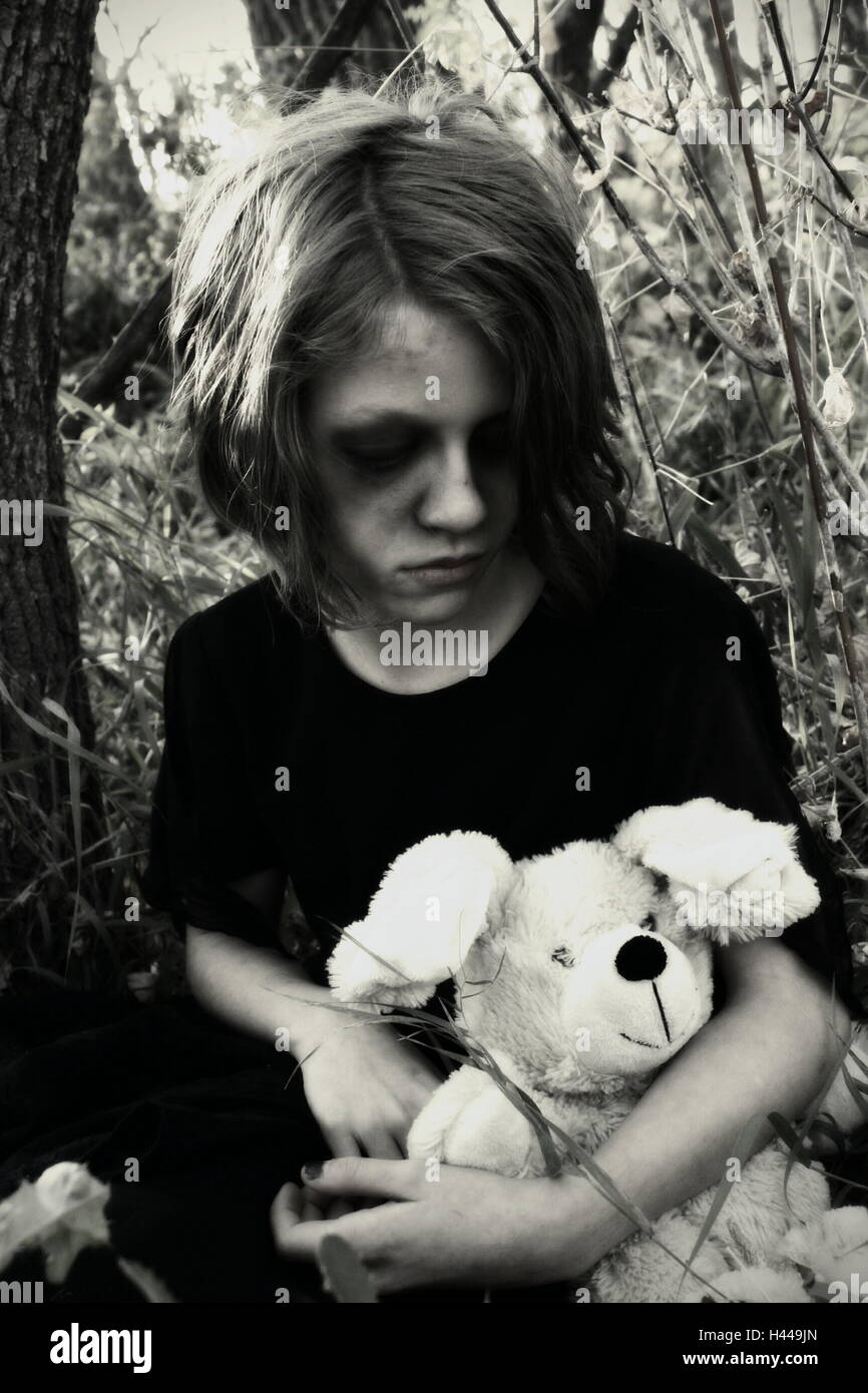 model holding a teddy bear looking morbid in a field Stock Photo