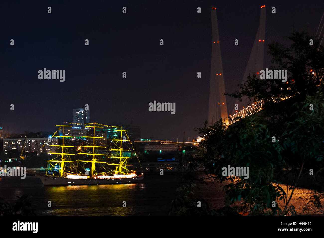 Night view on the sailboat near the bridge in the Russian Vladivostok over the Golden Horn bay. Stock Photo