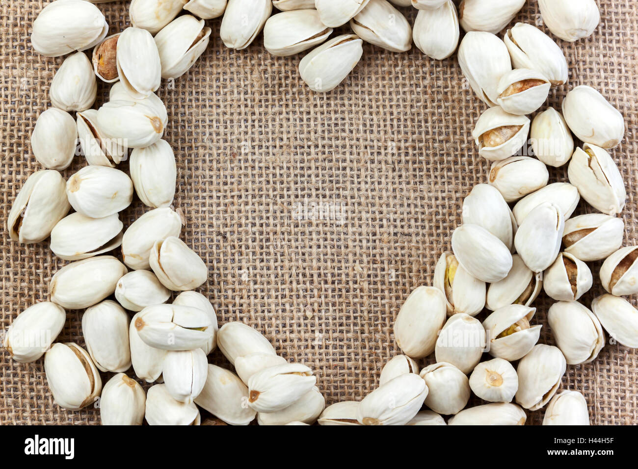 Roasted pistachio nuts with form heart shape on sacks background
