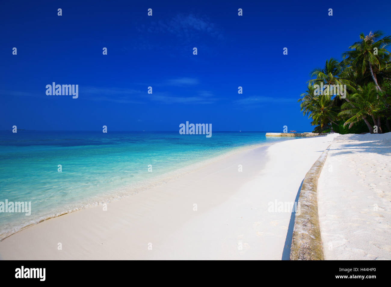 Tropical island with sandy beach with palm trees and turquoise clear water in Maldives Stock Photo