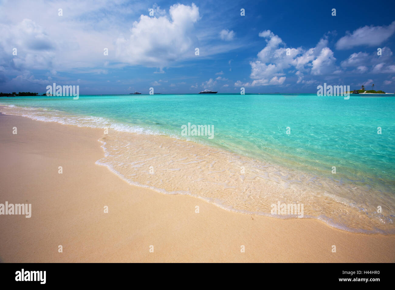 Tropical island with sandy beach with palm trees and turquoise clear water, Maldives Stock Photo
