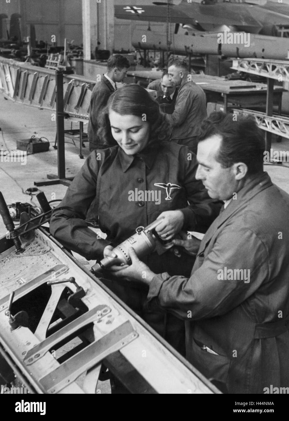 Germany, defense industry, Dornier, aircraft, training, 1942, economy, industry, factory, defense industry, occupation, defense, aerospace industry, military production, five, airplane factory, people, women, men, trainers, aircraft teach, Armor assistant, instruct, screwing, drilling, support, work, workbench, Dornier-Werke, nostalgia, historical, production facility, inside, Stock Photo