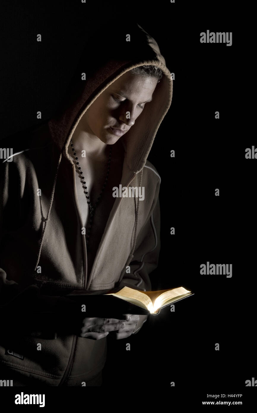 Man, young, view, prayer book, read, people, stand, hold necklace, rosary, faith, religion, Christian's tower, shirt, hood, hood shepherd, habit, brown, hands, book, gilt edge, prayers, pray, darkly, darkness, light, incidence light, portrait, curled, studio, cut out, Stock Photo