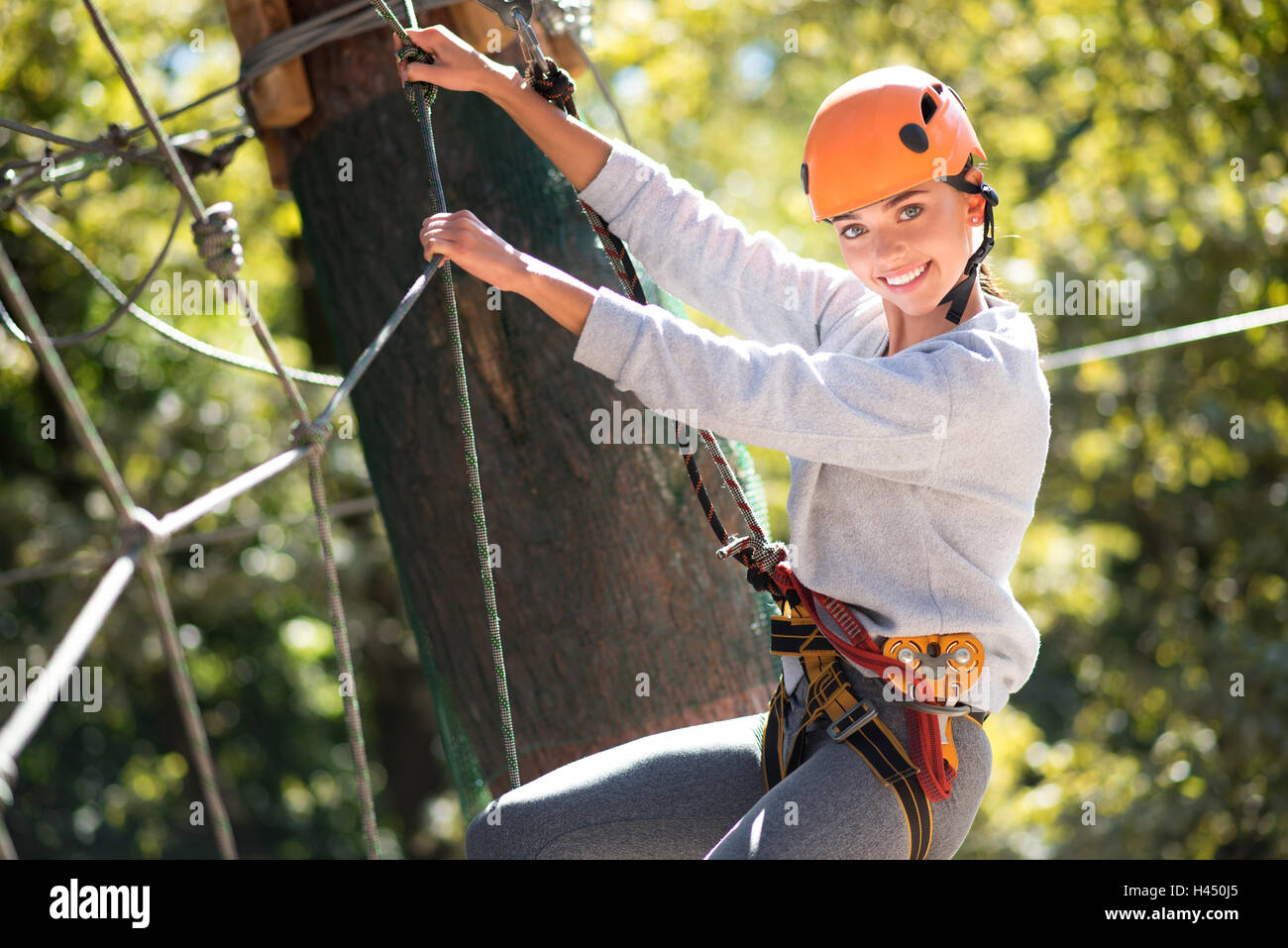 Brave skillful woman clambering in the high wire park Stock Photo