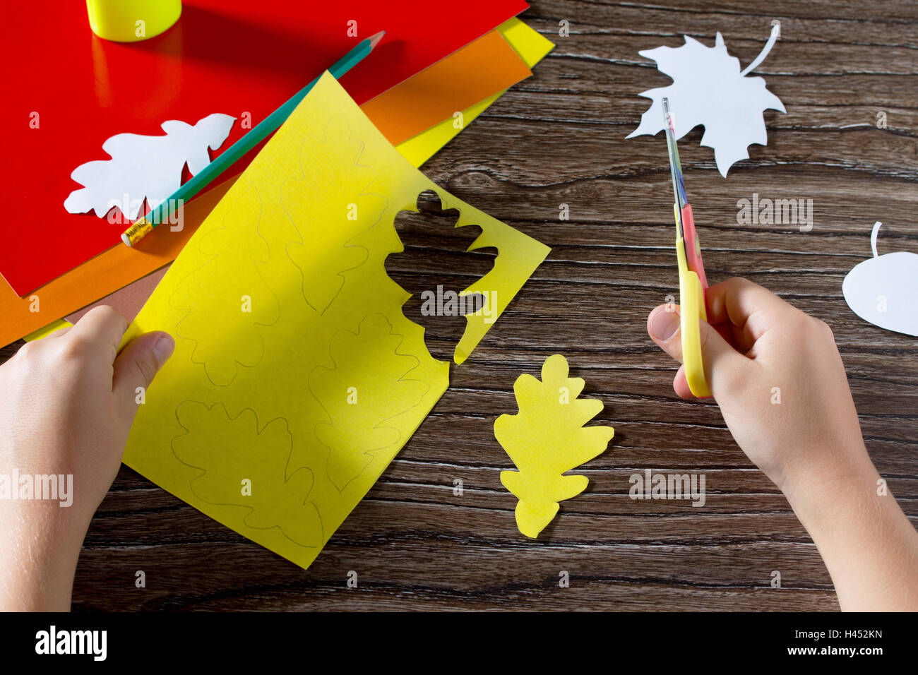 Autumn colored paper leaves on the wooden background. The child