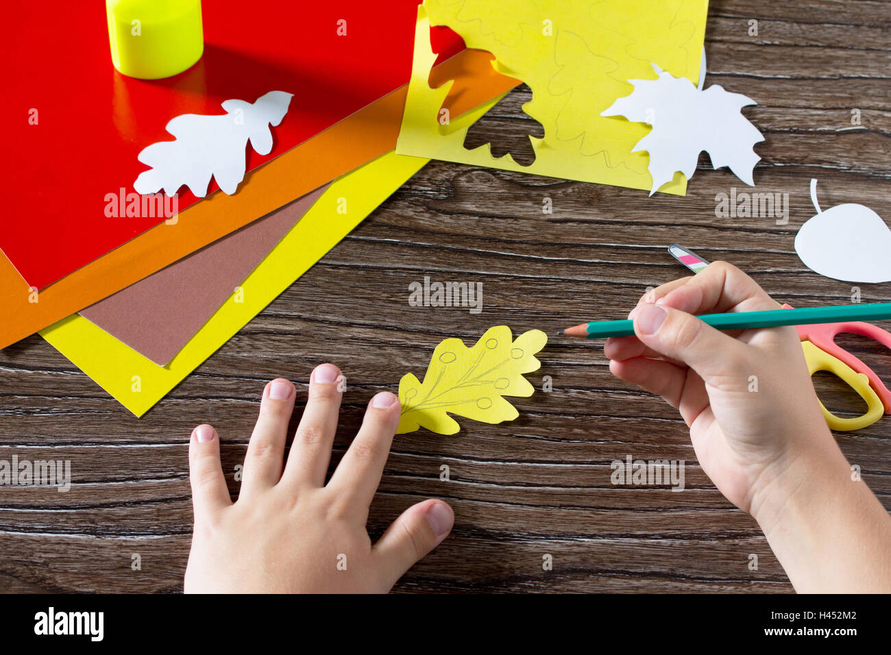 Autumn colored paper leaves on the wooden background. The child cuts out paper  leaves. Sheets of paper crafts for kids. Children Stock Photo - Alamy