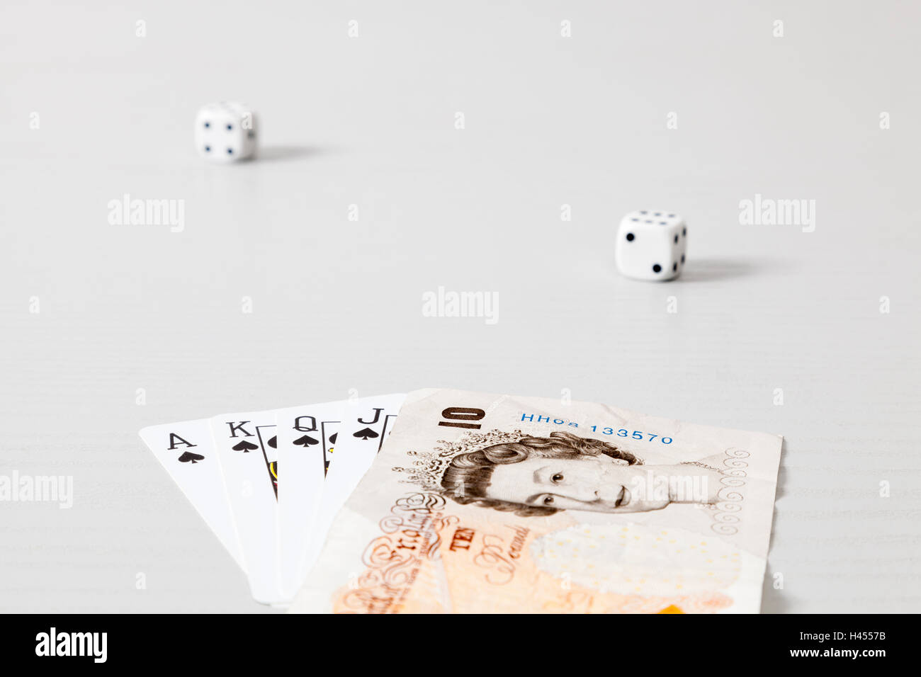 Betting or gambling concept. Dice and playing cards with £10 note instead of the ten of spades Stock Photo