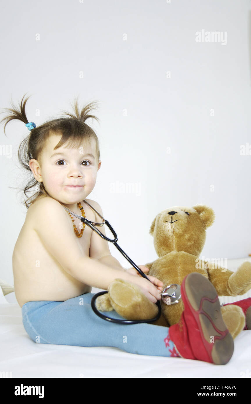 Girls, upper bodies freely, teddy, Stethoscope, listens to,   Series, child, 3-5 years, tights light-blue, slippers, necklace, material animal, plush animal, play, monitors, 'Dr. game', gaze camera, childhood, smiles freely, symbol doctor visit medicine, examination, control, provision, occupation wish, doctor,, Stock Photo