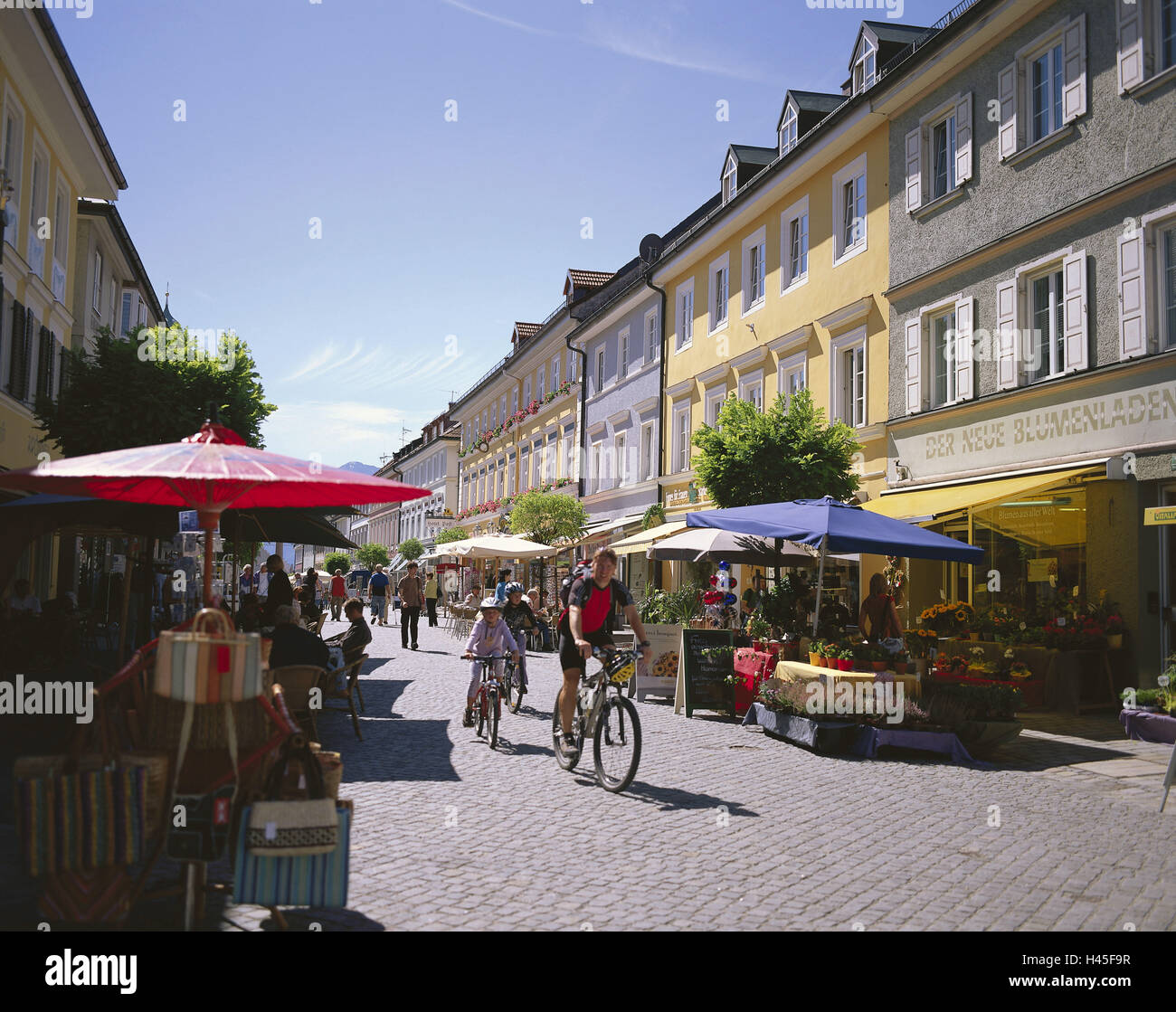 Germany, Bavaria, Murnau in the series lake, Marktstrasse, Upper Bavaria, city centre, street scene, cyclist, bicycle, houses, facade, shops, saunter, sunshades, flower shop, tourism, sales booths, shops, people, outside, house line, architecture, summer, sunny, Stock Photo