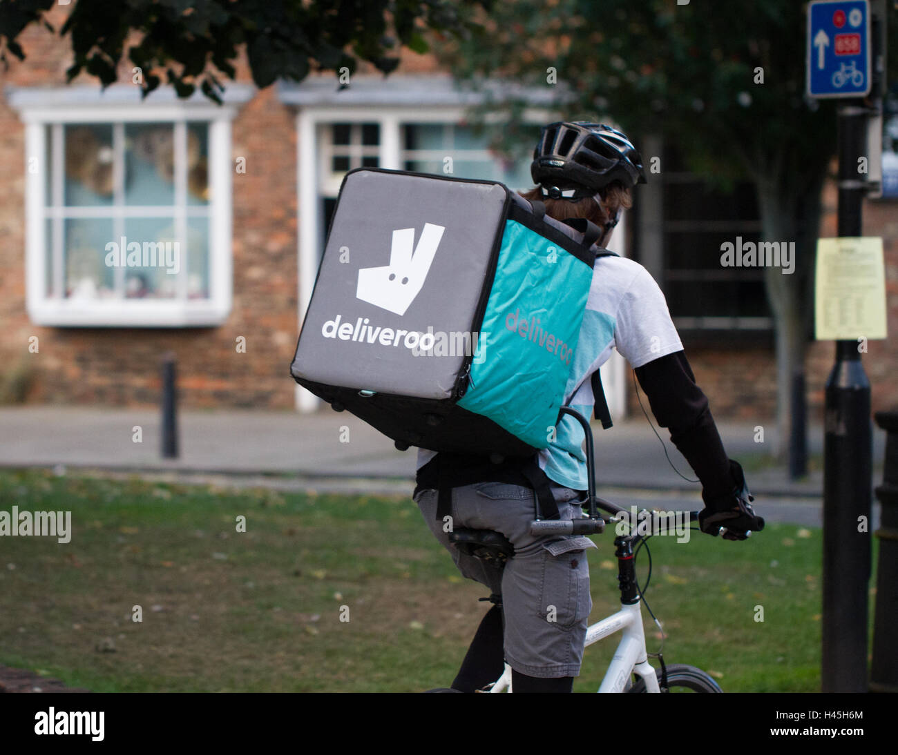 A Deliveroo cyclist from the increasingly popular hot food and fast food delivery company cycling through city streets. Stock Photo