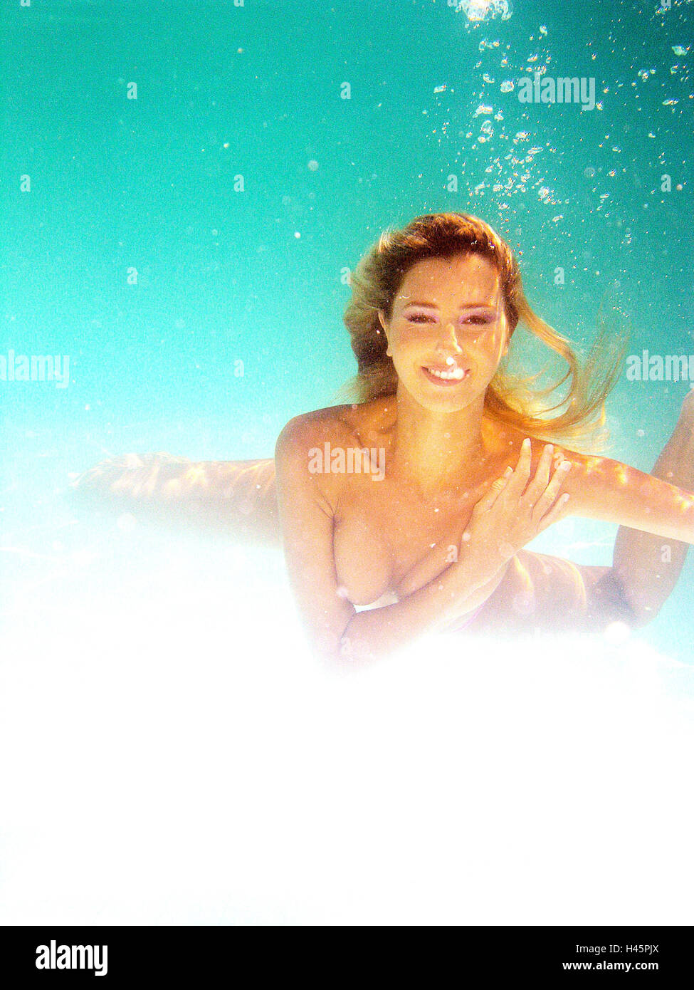 Woman, young, upper bodies freely, dives,  Pool, underwater reception,   Series, 27 years, 20-30 years, blond, long-haired, nicely, attractively, smiling, gaze camera, breasts cover, swims, swims, under water, pools, Swimmingpool, sunny, summer, air bubbles, concept, mermaid, water nymph, grace, beauty, pliability, dream, illusion, back light, Stock Photo