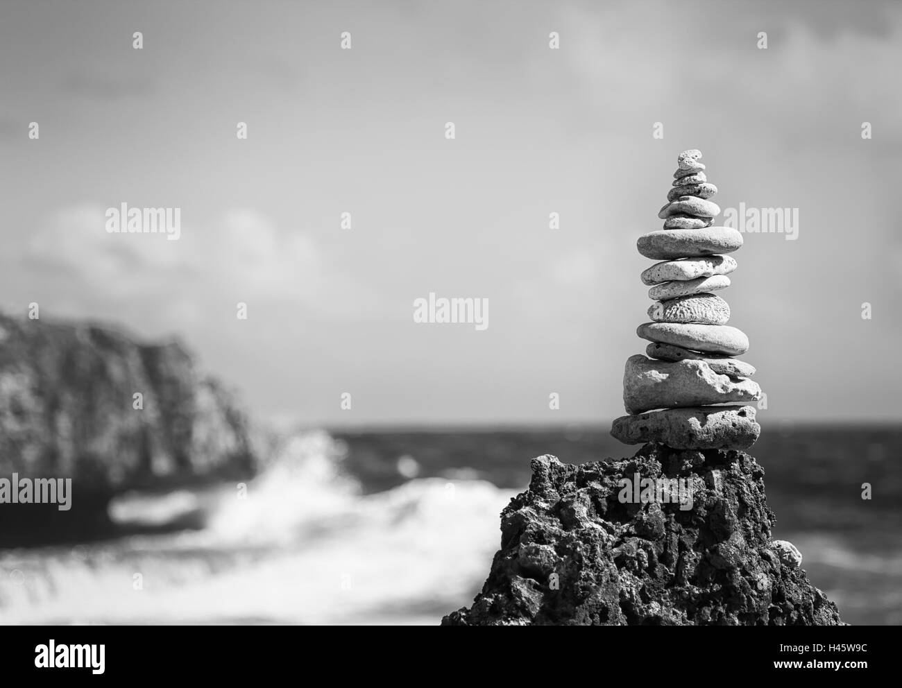 pile of pebbles on a rock at the ocean, black and white image Stock Photo