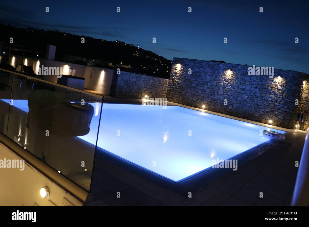 Pool and town in Mykonos, Greece, lit up during dusk Stock Photo