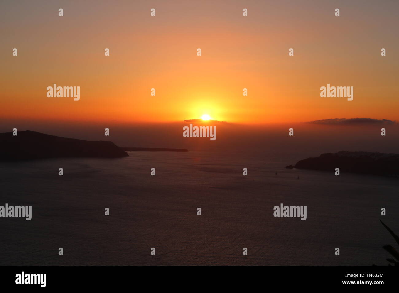 Serene sunset emitting bold red and orange hues over the caldera in Santorini, Greece Stock Photo