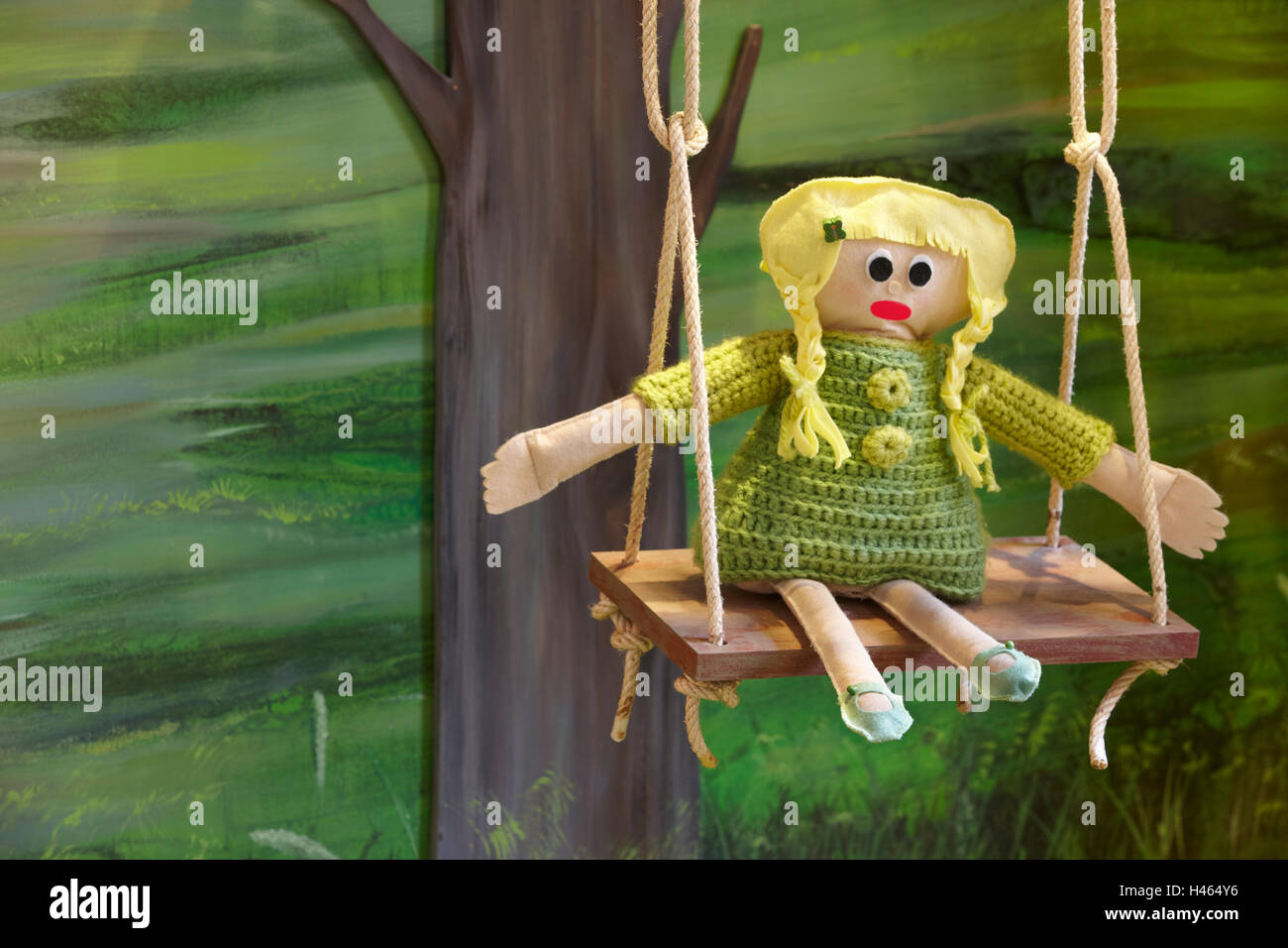 Stuffed doll over a swing with a forest background. Horizontal Stock Photo