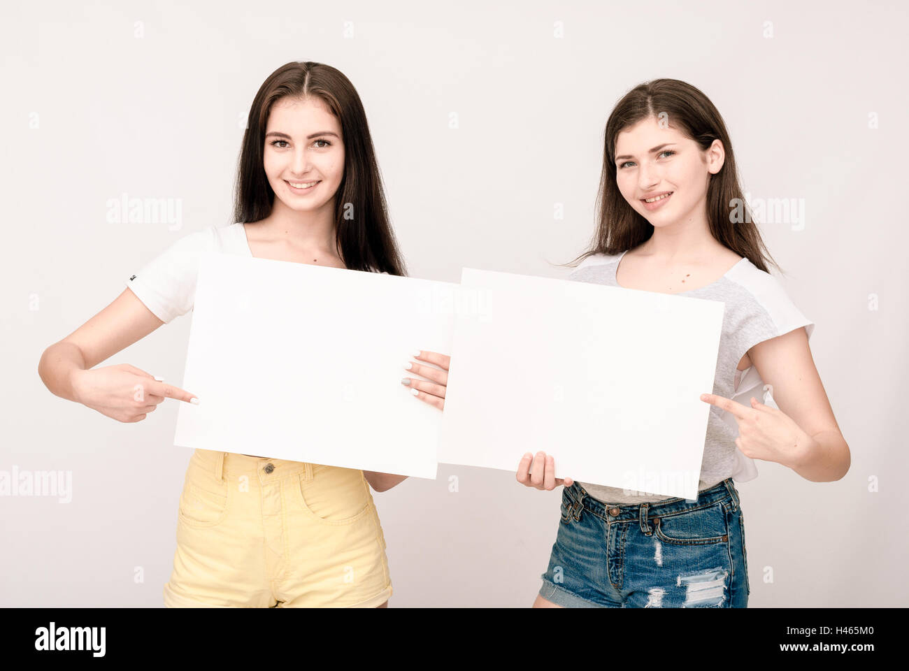 Two happy smiling young women carring big blank signboard Stock Photo