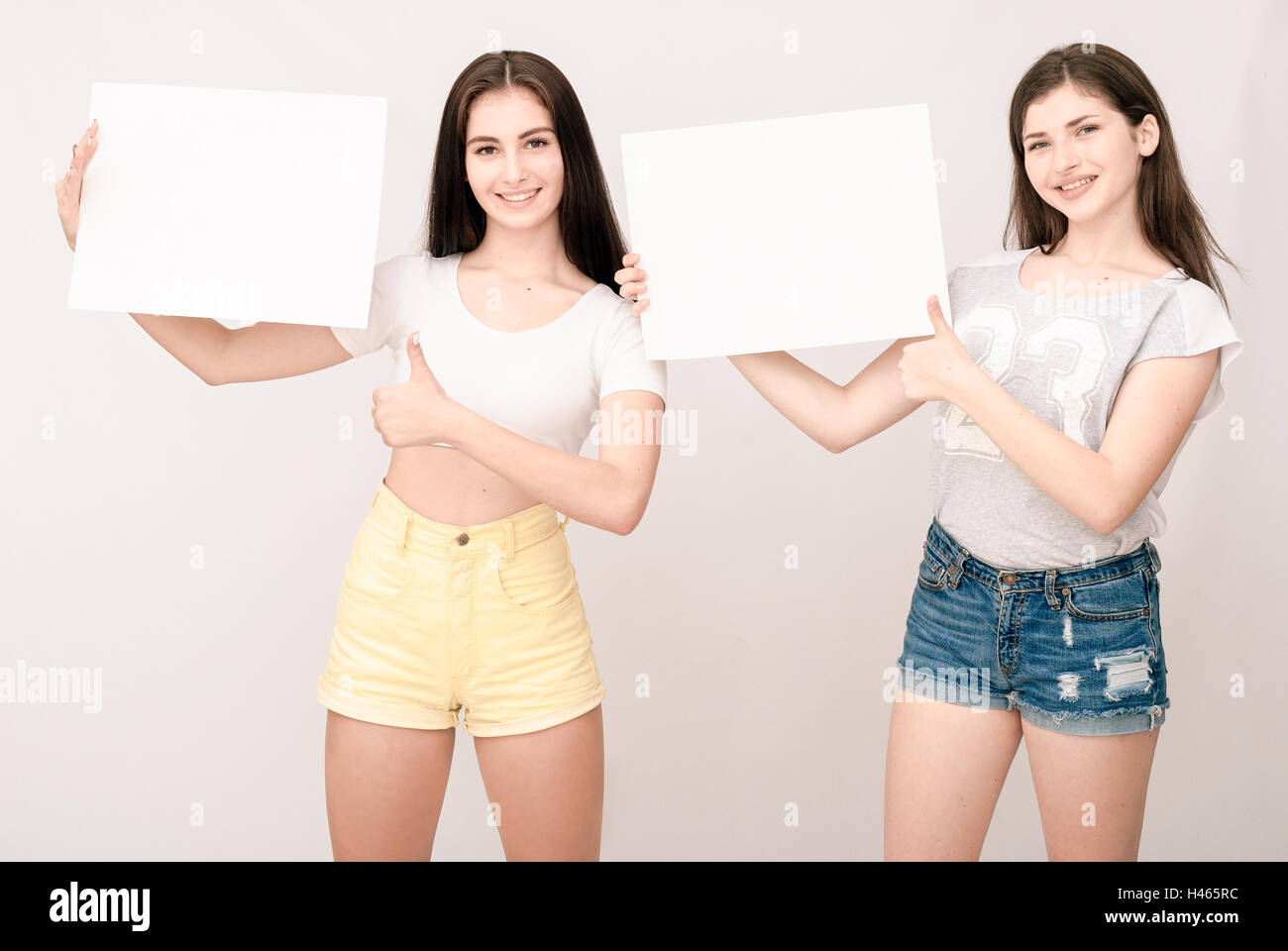 Two happy smiling young women carring big blank signboard Stock Photo