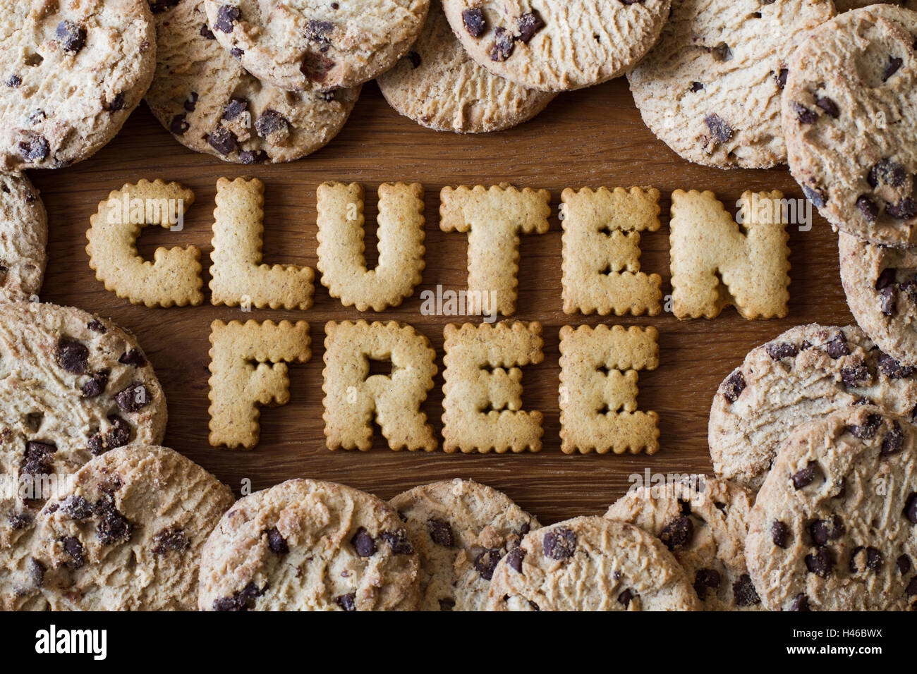 The food advice 'Gluten Free' spelled with alphabet shaped cookies and surrounded by gluten free, chocolate chip cookies on wood Stock Photo
