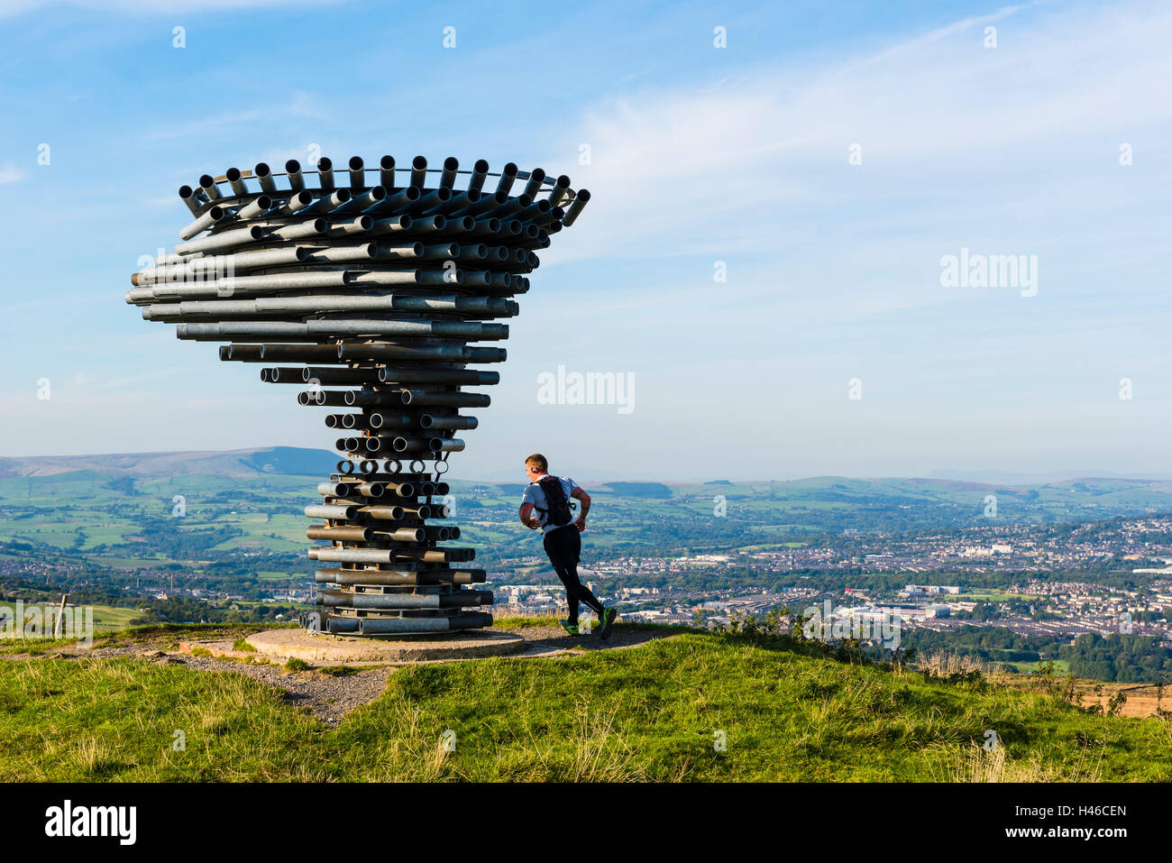 Runner at the Singing Ringing Tree panopticon on Crown Point in the Lancashire Pennines, looking towards Burnley and Pendle Hill Stock Photo