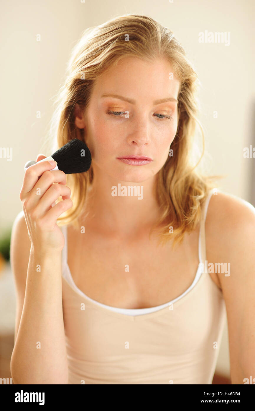 Blond woman with make-up brush, seriously, Stock Photo