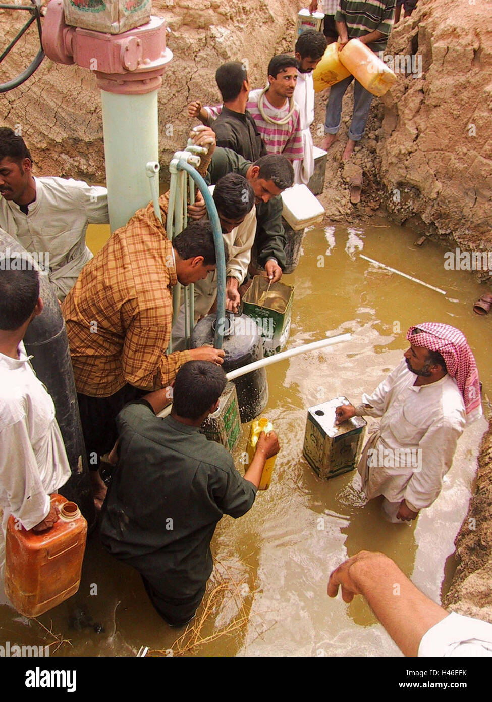 15th April 2003 Just south of Ur, near Tallil, local Iraqis use hoses to tap a pipeline and fill plastic containers with petrol. Stock Photo