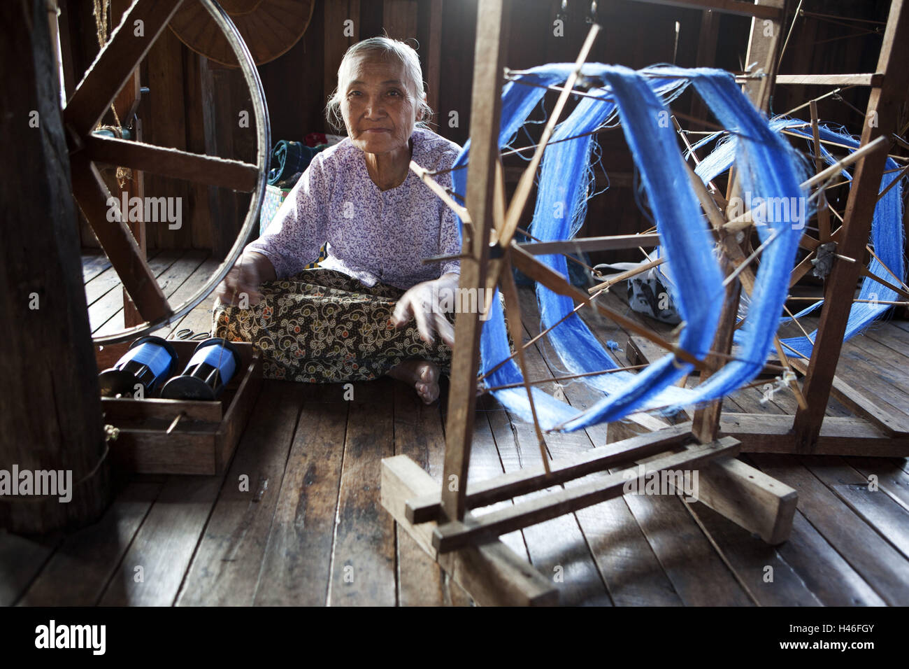The mysterious old lady is rolling a traditional spinning wheel in