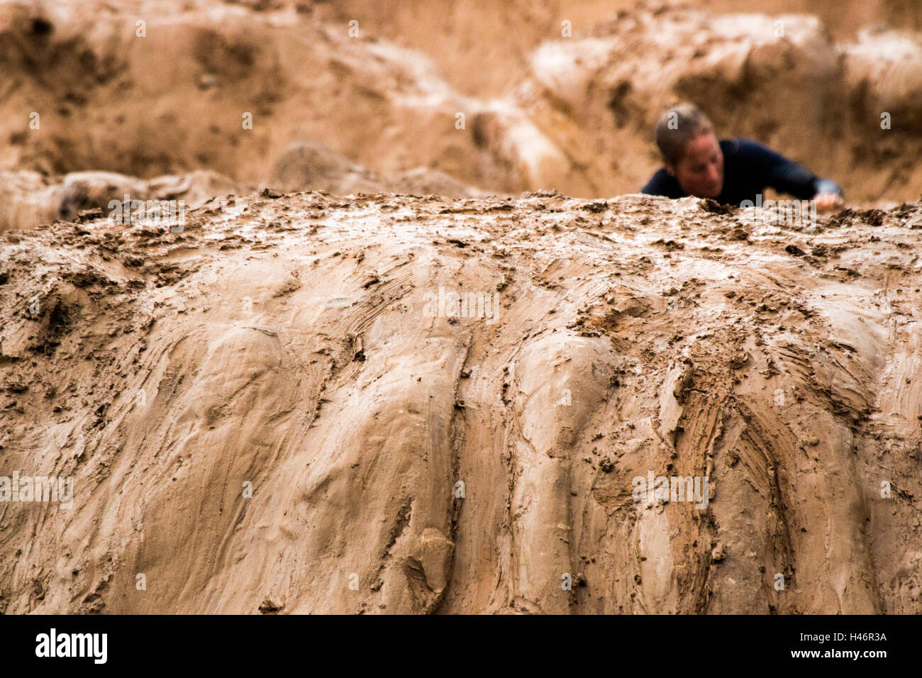 Tough Mudder competitor at an obstacle going through the Mud Mile 2.0 Elkhart Lake WI (athlete not in focus, foreground in focus Stock Photo