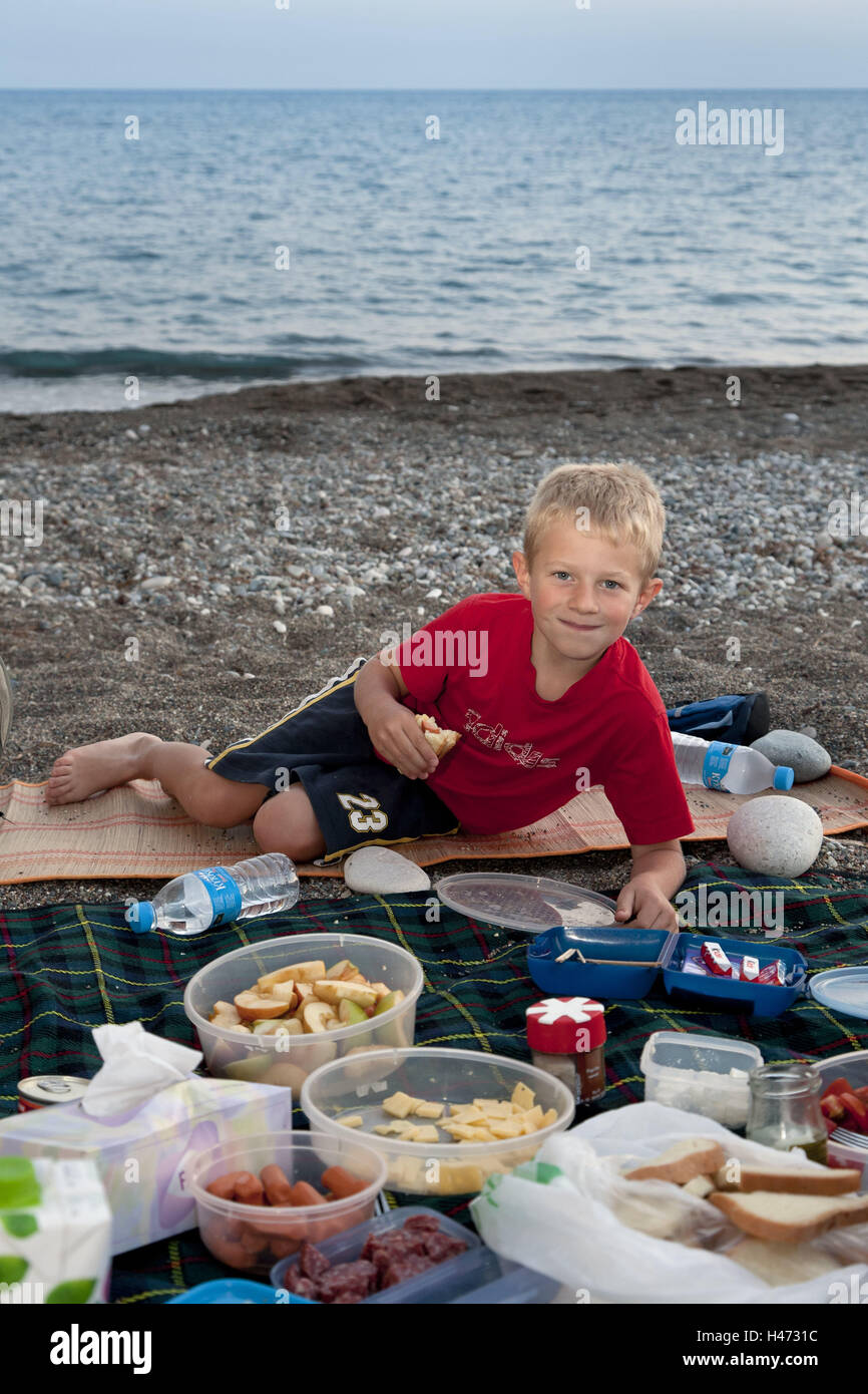 Boy, view camera, smile, eat picnic, beach, Aphrodite rock, to Südzypern, Southern, Europe, Europe, Cyprus, people, child, happy, snack, in Greek, south part, island, in of a Cypriot manner, rest, relax, there has of a picnic, beach, sea, food, outside, Stock Photo