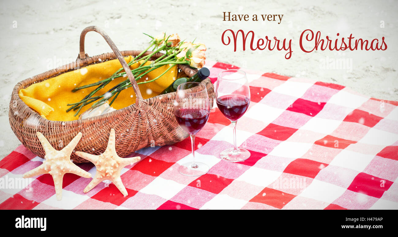 Christmas card against picnic basket with glasses of red wine and starfishes on blanket Stock Photo