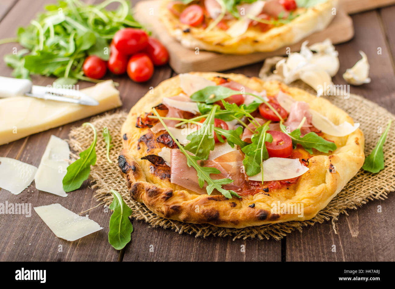 Italian pizza with parmesan cheese, prosciutto and arugula, home made