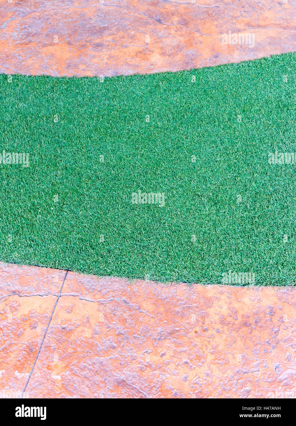 Artificial grass strip in the stone pathway of the small garden Stock Photo