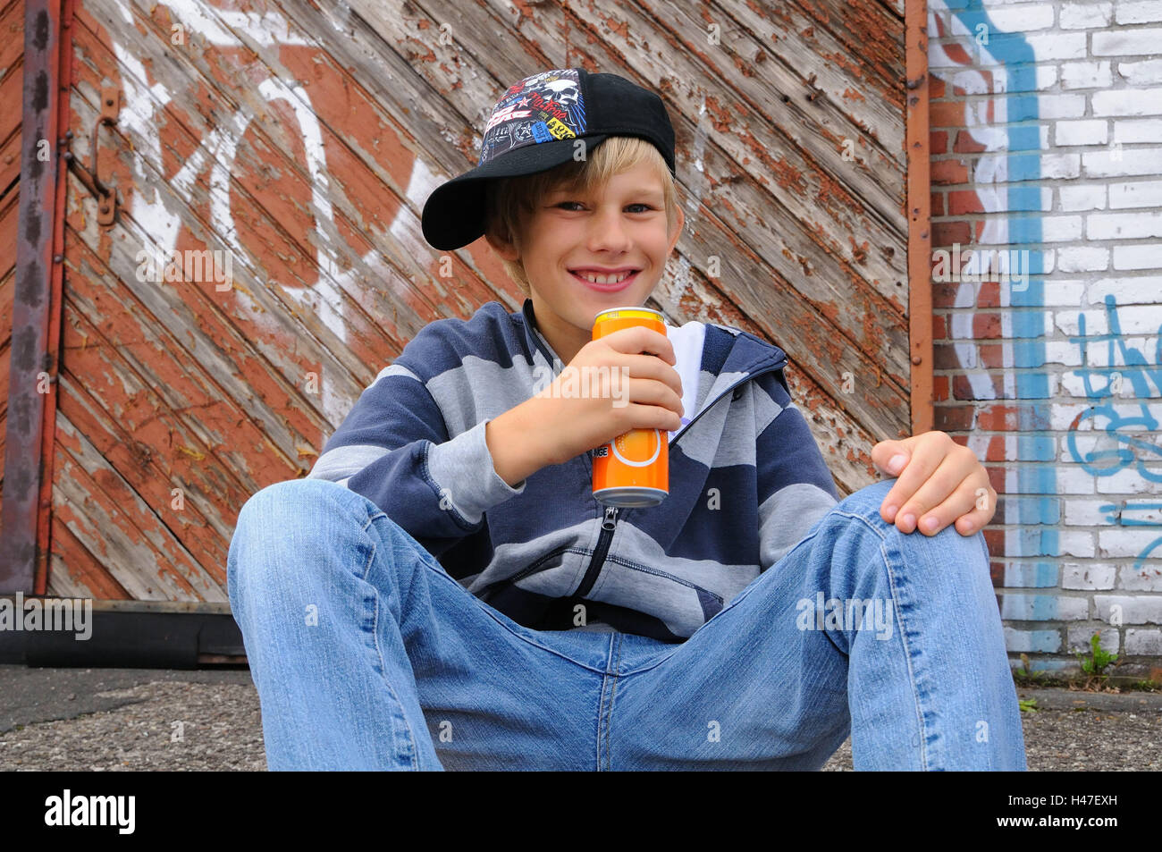 Boy, baseball cap, drinks can, sit, smile, view camera, kids, young persons, playing skat, skaters, cap, break, happy, smile, drink lighthearted, childhood, youth, cap, outfit, careless, youth culture, cleverly, mischievously, industrial scales, leisure t Stock Photo