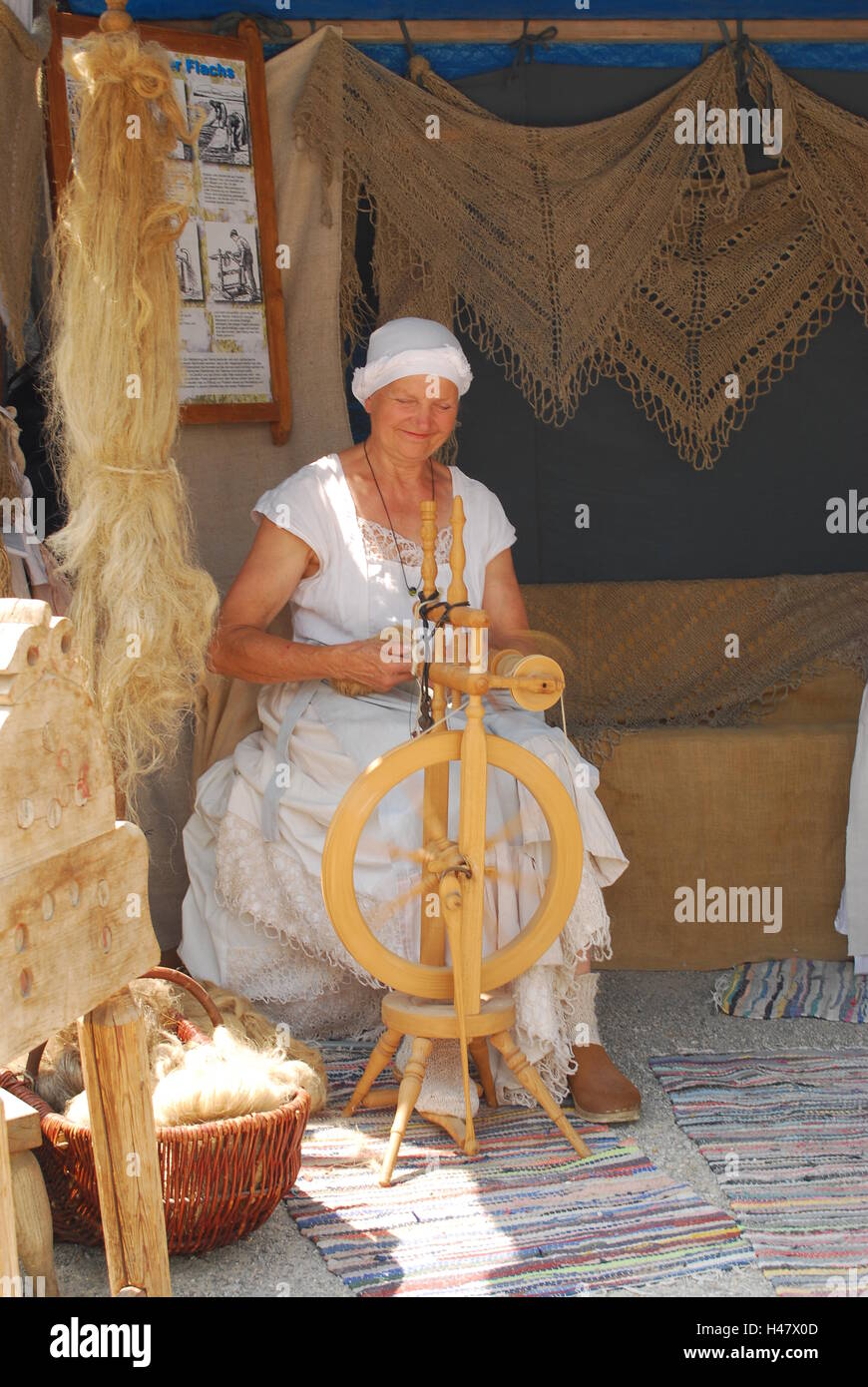 A woman in medieval dress spins wool Stock Photo