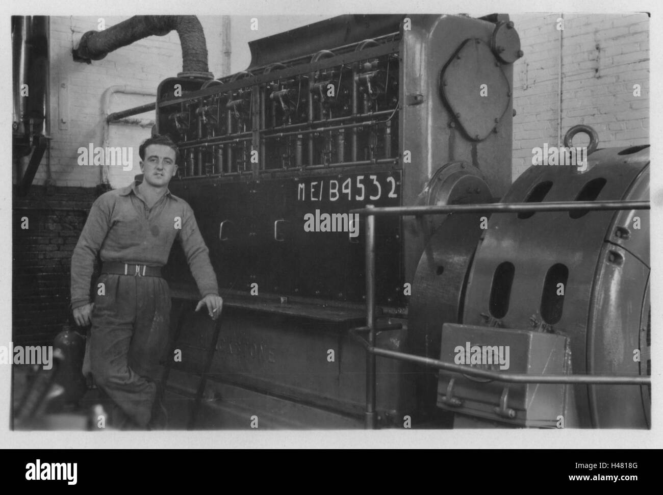 British army engineer identified as John Cotterell standing next to a Mirrlees Blackstone diesel generator nicknamed The Mighty Whirlitzer. Photo taken in 10 Base Ordnance Depot Royal Army Ordnance Corps (RAOC) camp at Geneifa Ismailia area near the Suez Canal 1952 Egypt. Stock Photo