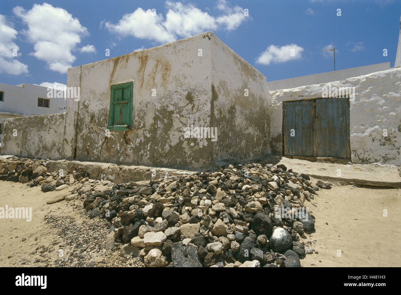 Spain, the Canaries, island La Graciosa, Caleta del Sebo, Dorfstrasse, houses, architecture, street, dusty, heat, wilderness, defensive wall, clouds, heavens, residential houses, exit, outside, deserted, stones, stone heaps, Stock Photo
