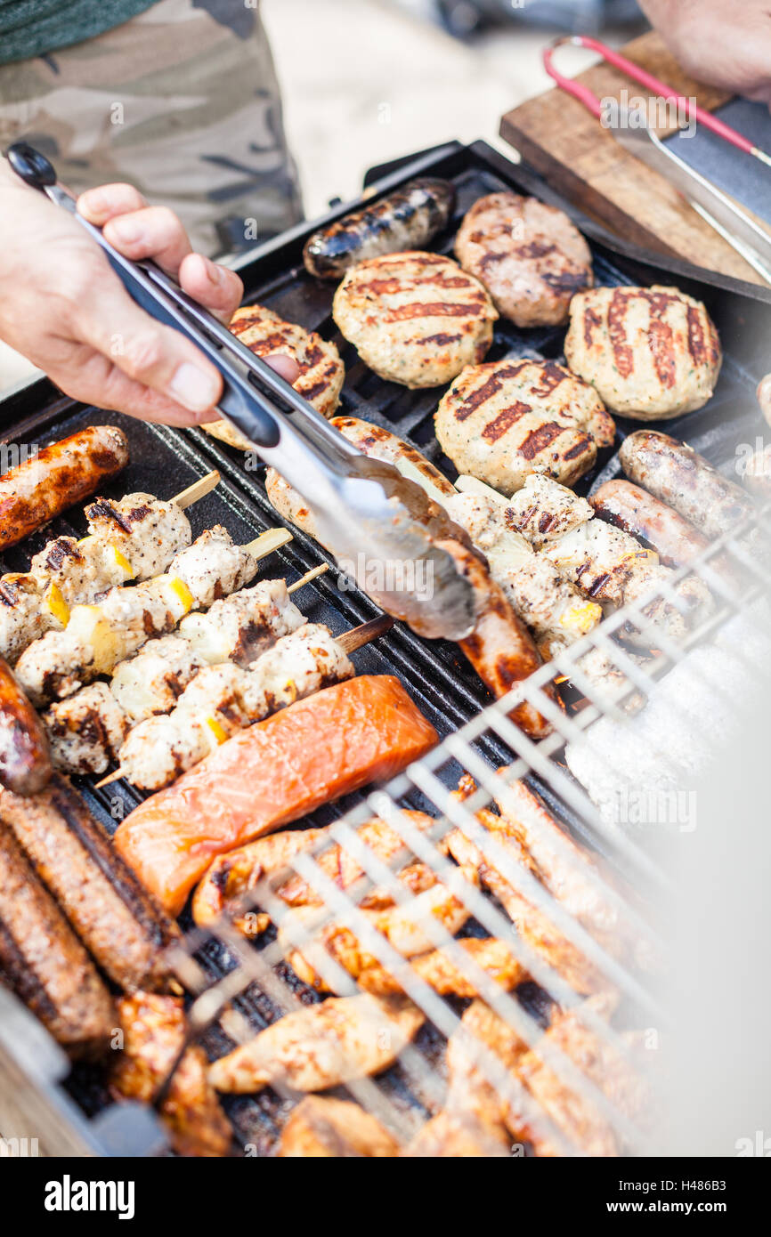 Smokey gas barbeque cooking various meats (burgers, sausages, fish