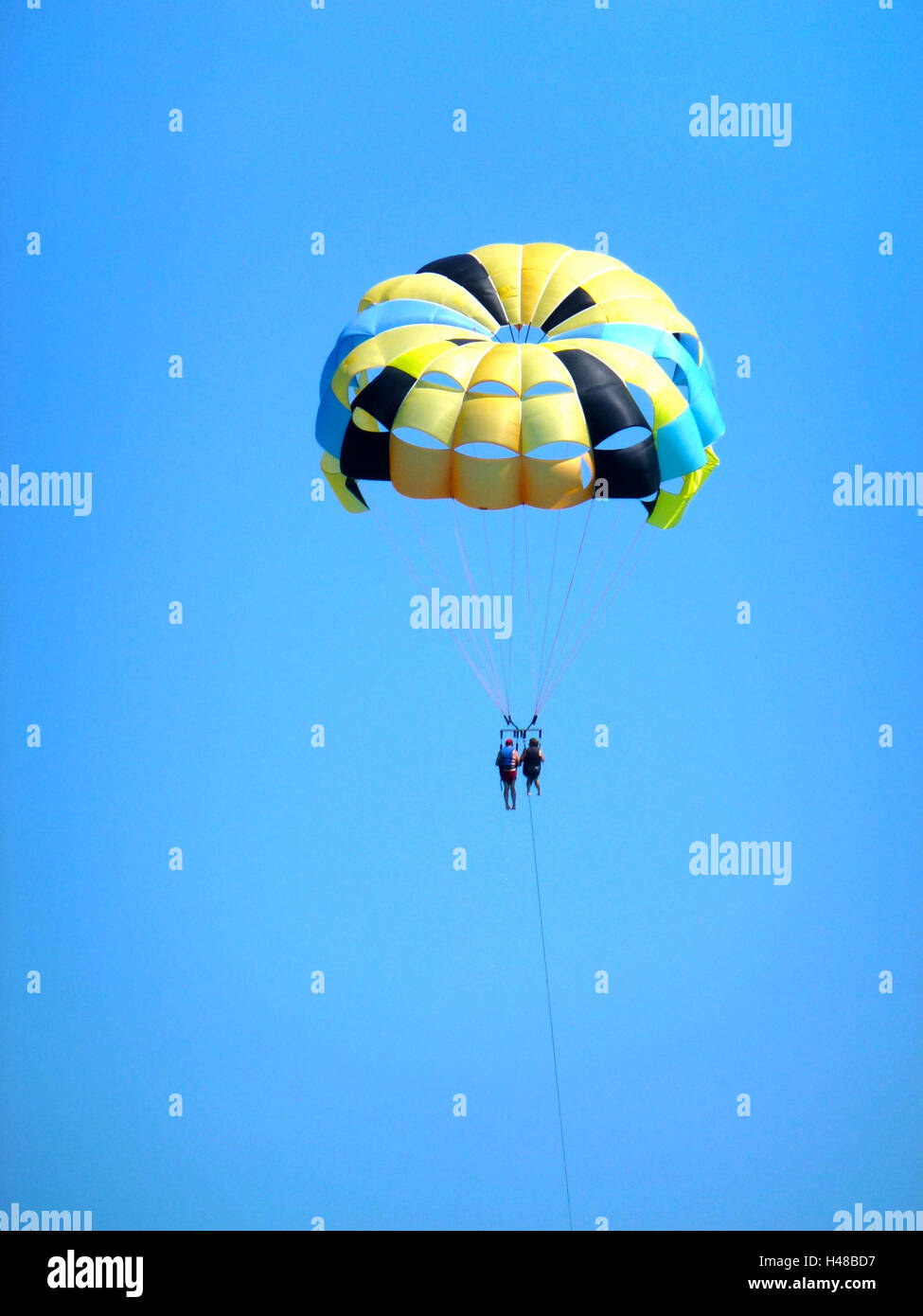 Parasailing in the blue sky, coloured parachute, two people, Stock Photo