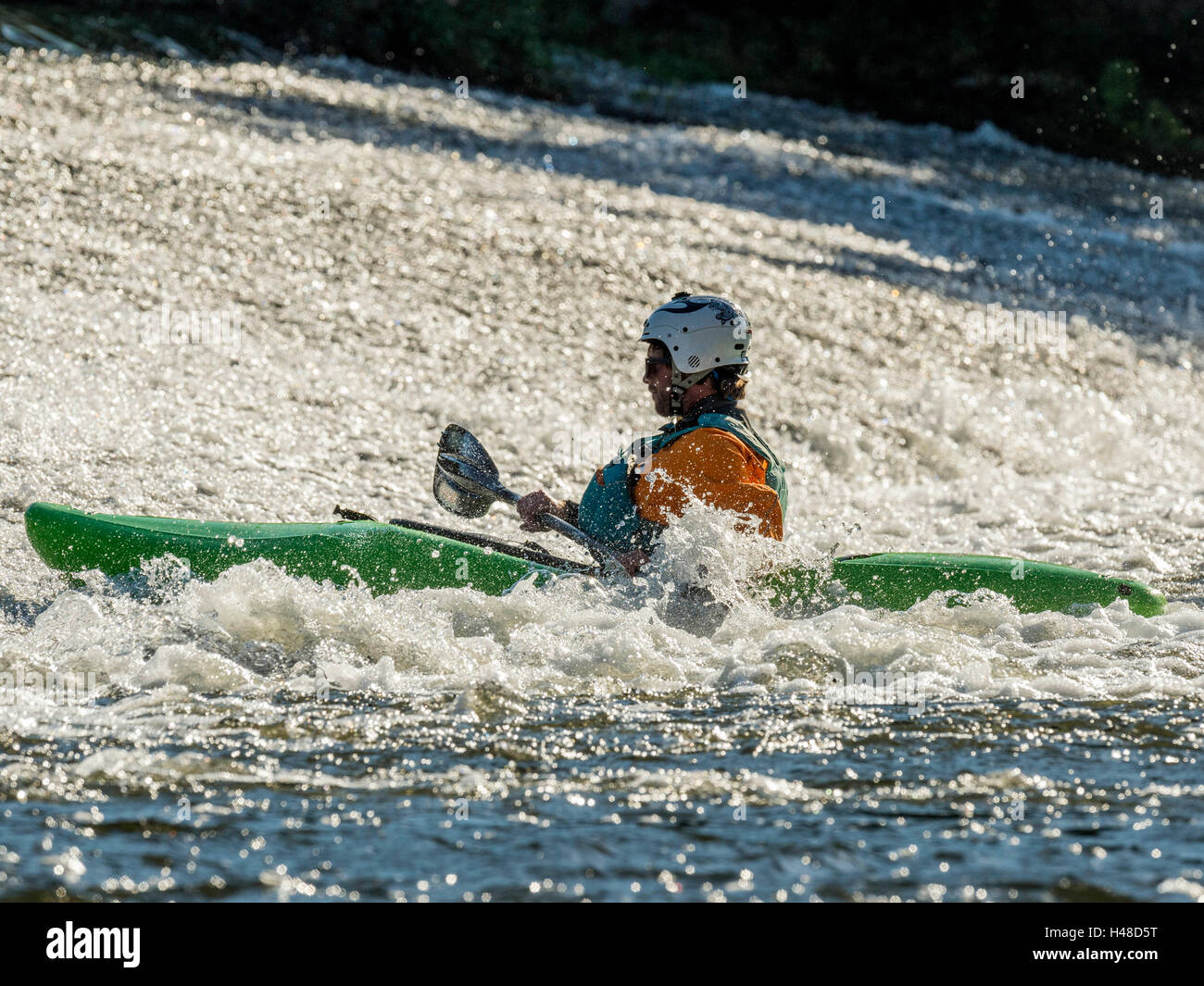 Male adult White Water Kayaking along a River Exe Weir on a bright Autumn day. Situated near Exeter in Devon, United Kingdom Stock Photo